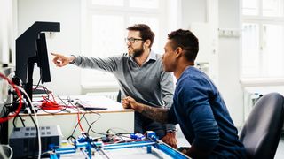 Two engineers discussing a project in front of a computer.