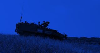 Mid-size military vehicle traversing tall grass.