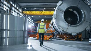 Engineer walking through a steel and metal manufacturing facility with safety attire.