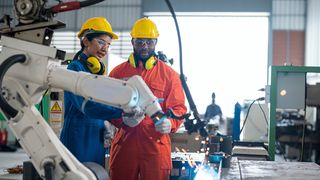 Male and female engineers discussing a project while looking at working robotics equipment.