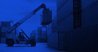 Crane lifting up a storage container in a port.