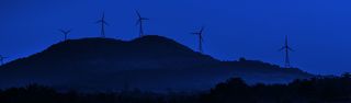 Landscape view of a wind turbine field on a hill with a blue color filter over top.