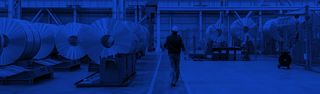 Engineering worker walking through a steel warehouse.